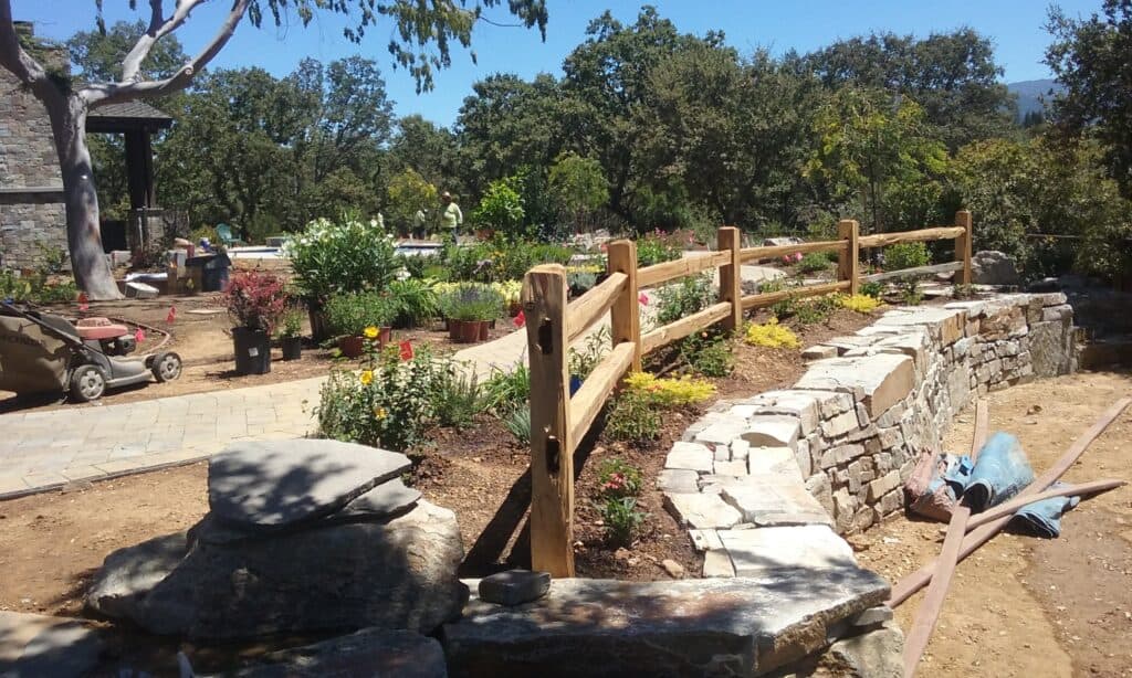 Detailed image of garden landscaping with stone wall, pathway, and plants.