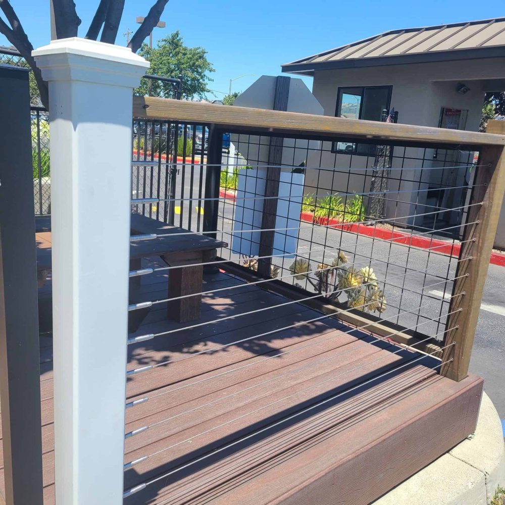 Durable wooden deck with sleek metal railing, perfect for outdoor entertainment, by Odie Landscaping.